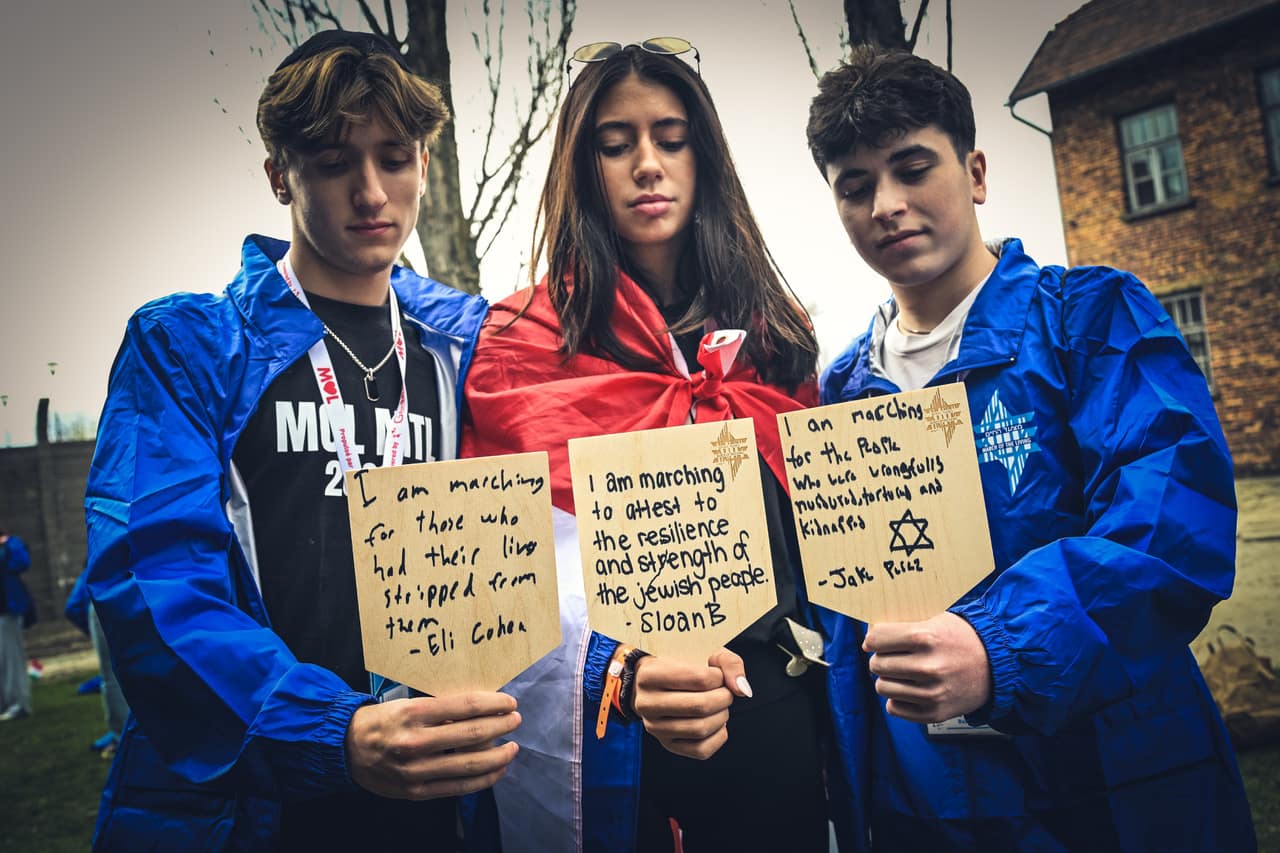 Participants holding handwritten memorial plaques